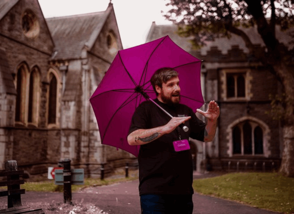 A Tour Guide giving a dark dublin tour standing outside christ church cathedral holding a purple umbrella