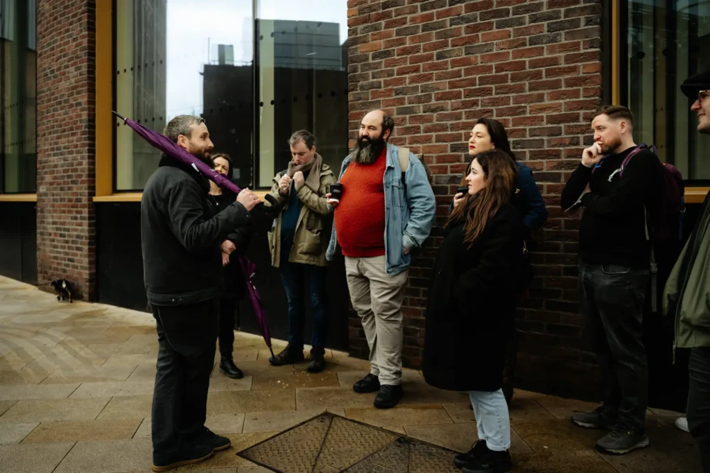 A group standing tourists receiving a tour from a dublin tour guide standing on the street corner next to guinness